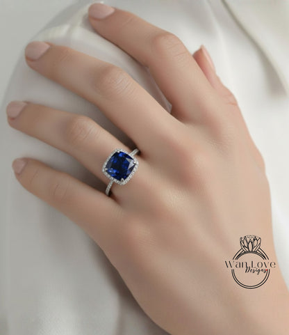 A close-up of a hand wearing a diamond ring with a large blue gemstone.