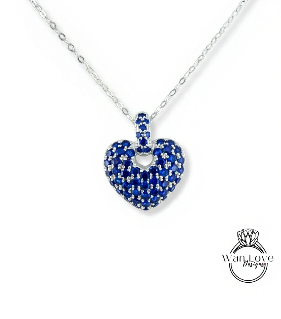 A silver necklace with a heart-shaped pendant made of blue sapphires.