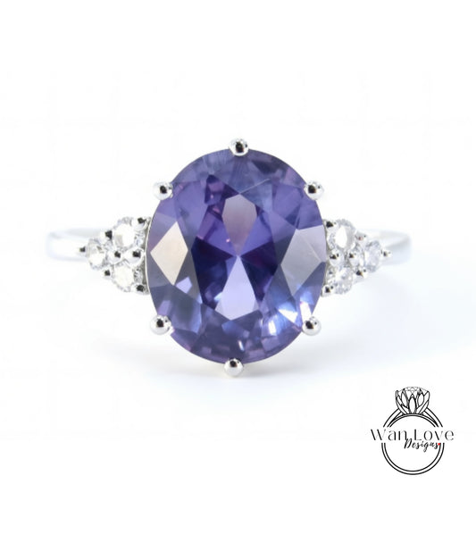 A silver ring with a large oval-shaped purple gemstone, surrounded by smaller diamonds.