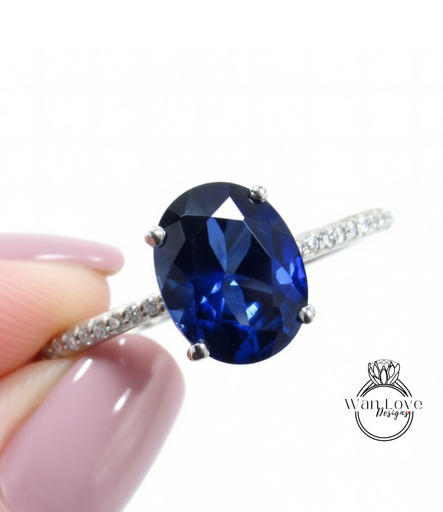 A close-up image of a person's hand holding a ring with a large blue gemstone, likely a sapphire or blue topaz.