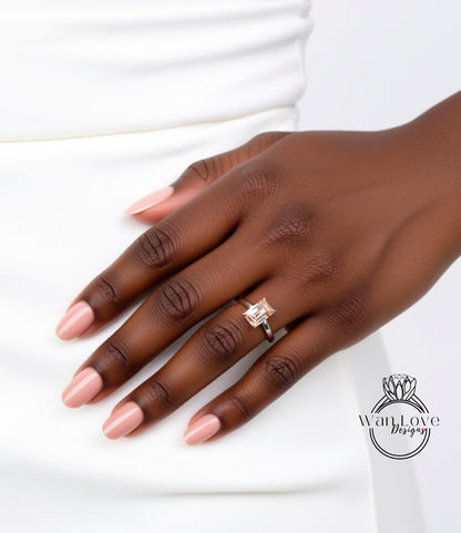 A close-up of a hand wearing a diamond engagement ring, with a white dress visible in the background.