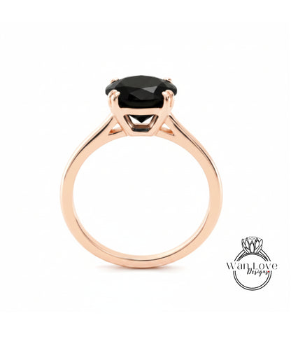 A rose gold engagement ring with a large black gemstone set in the center.
