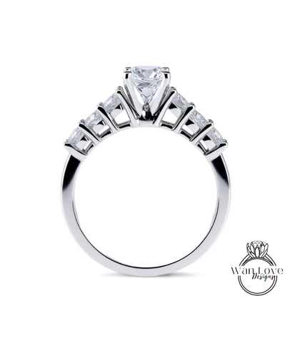 A close-up view of a silver engagement ring with a large central diamond surrounded by smaller diamonds arranged in a fan-like design on the band.