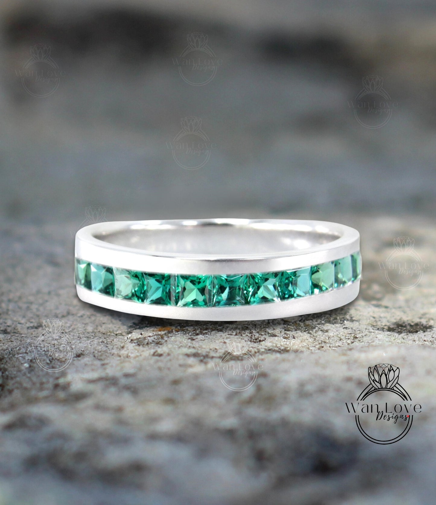 a white gold ring with green stones on it